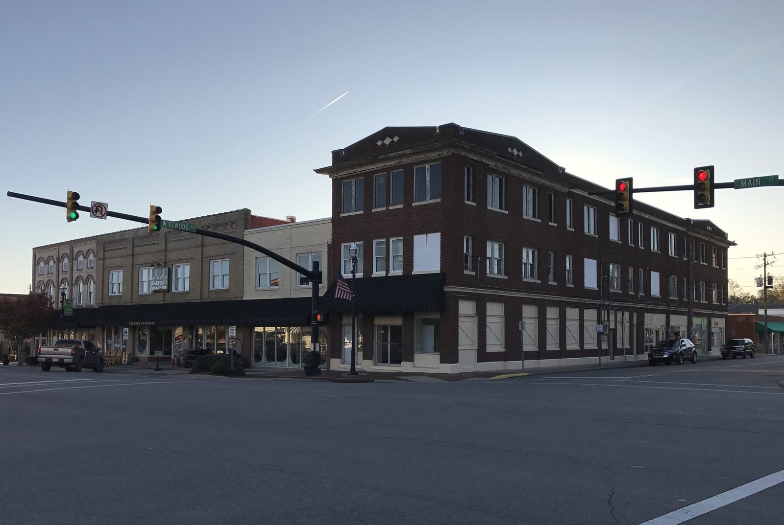 Brick commercial buildings at a corner in downtown Raeford under a clear sky