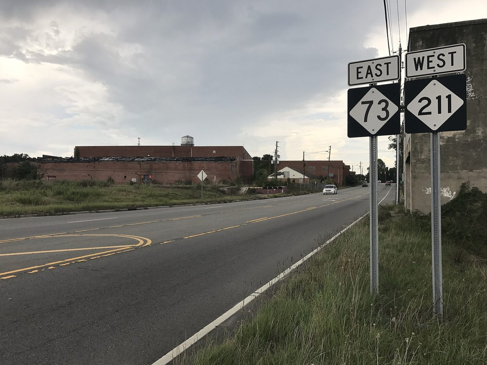 Route signs for NC 73 East and NC 211 West beside a two-lane road